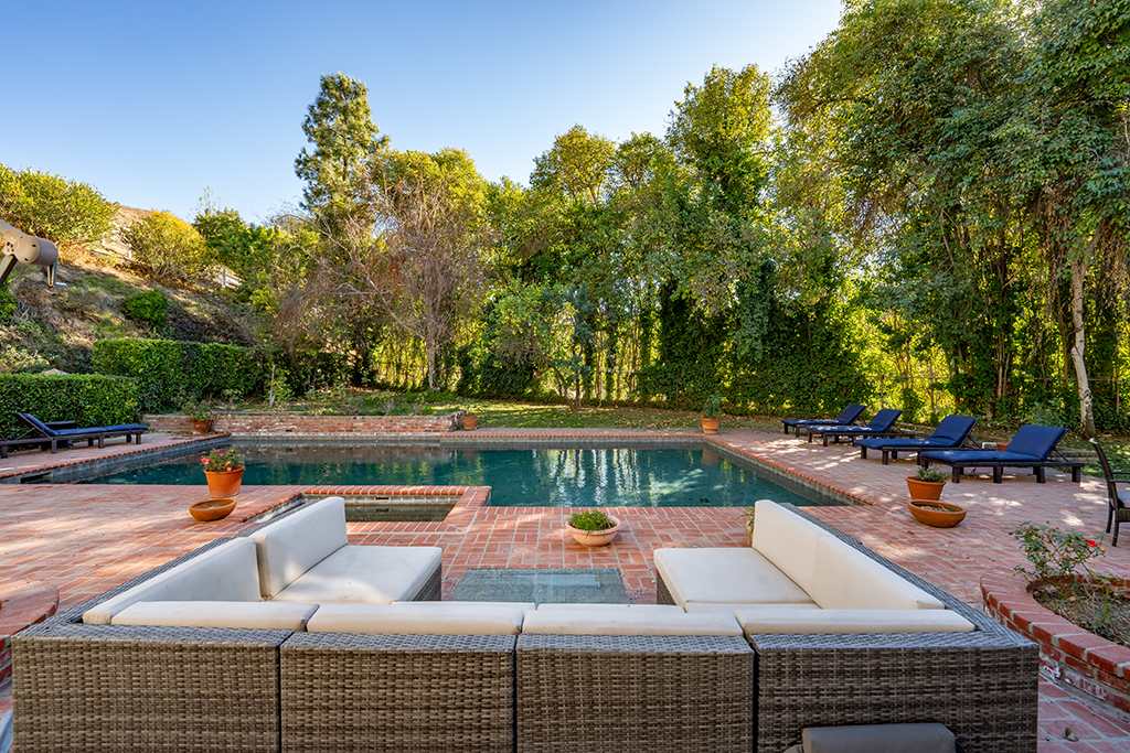 Poolside Lounge Area | The Agency Journal Outdoor poolside lounge area surrounded by mature trees