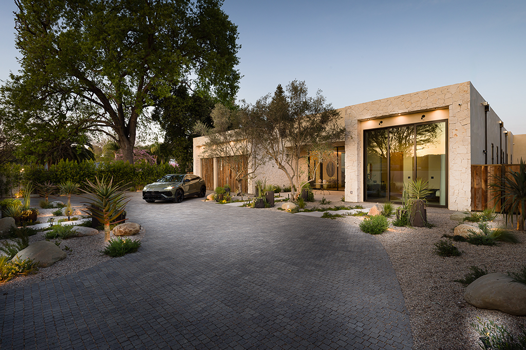 Front view of the home's exterior with driveway with trees to the left