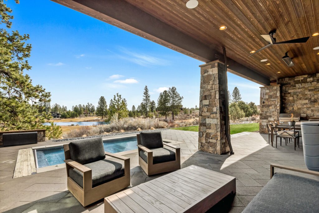 an outdoor living space featuring a swimming pool and patio area. The space is furnished with two armchairs, a coffee table, and a sectional sofa