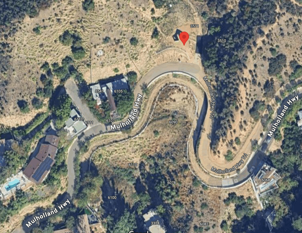 Aerial view of a winding section of Mulholland Highway in Los Angeles, showing houses nestled in a hilly, green landscape, with street names visible and a mix of natural and residential surroundings.