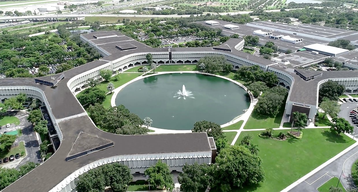 Aerial view of the BRiC campus, featuring a large building and a central pond, home to various organizations including Canon.