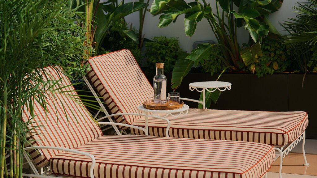 Pair of white outdoor lounge chairs with red and white striped cushions on a hotel rooftop pool deck.
