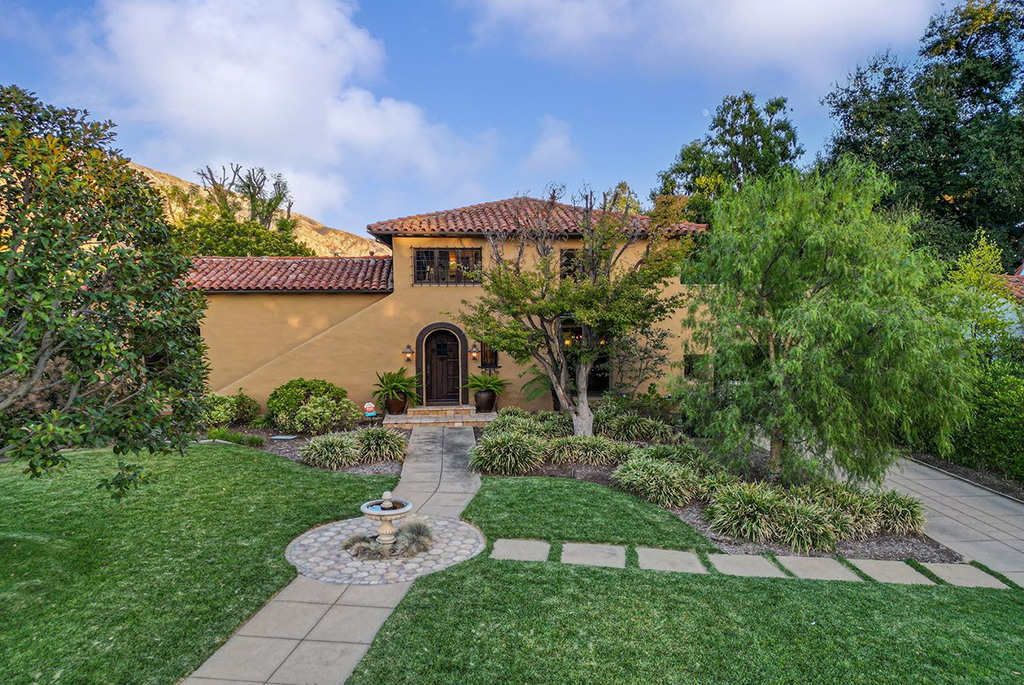 Front exterior of a 1927 Spanish Revival estate at 2092 Midlothian Drive, Altadena, CA, featuring a terracotta tile roof, stucco walls, an arched doorway, and mature landscaping