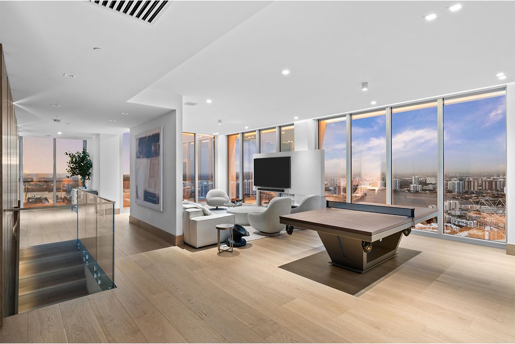 Modern high-rise living space with light wood floors, neutral furniture, and panoramic urban views.