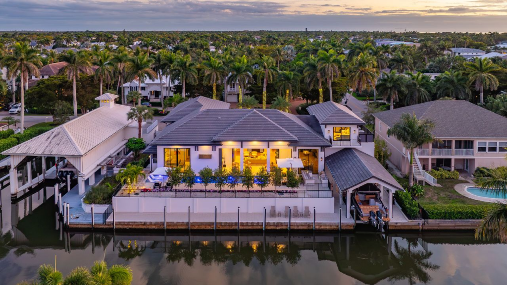 Waterfront luxury home in Aqualane Shores Naples FL with boathouse, pool, palm trees, and canal view
