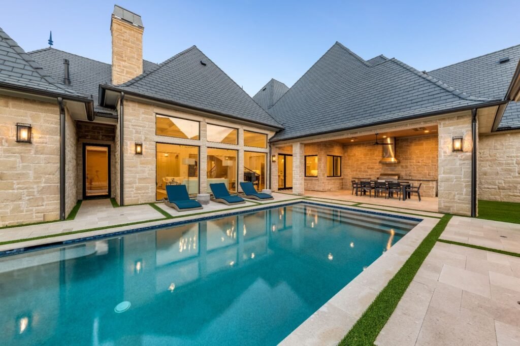 Luxury backyard in Frisco, TX with geometric swimming pool, sun loungers, and covered outdoor kitchen with built-in grill.