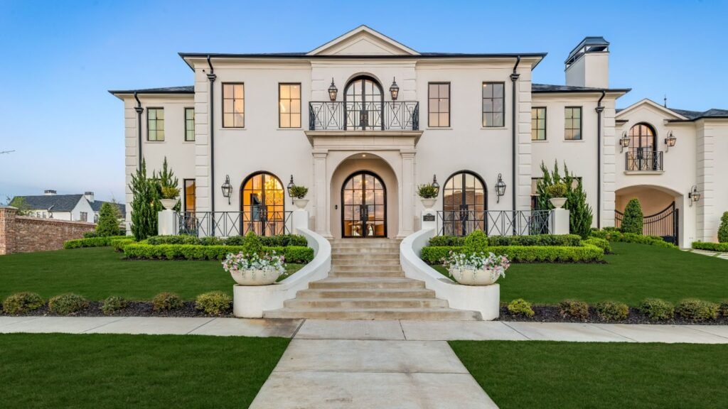Symmetrical French Provincial luxury mansion in Frisco, TX with grand stone staircase and arched black iron doors.