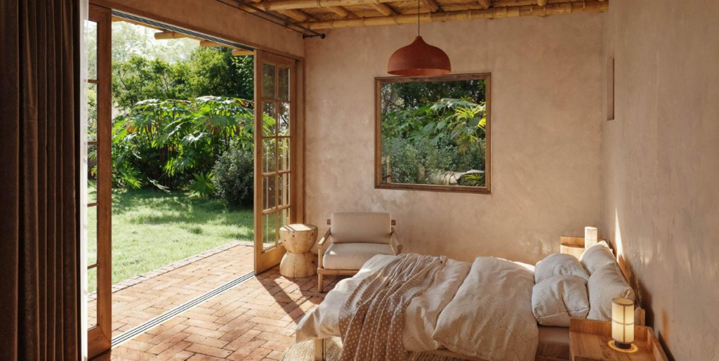 Sustainable bedroom in Playa Negra, Costa Rica, with bamboo ceiling, clay tile floors, and doors opening to a lush garden.