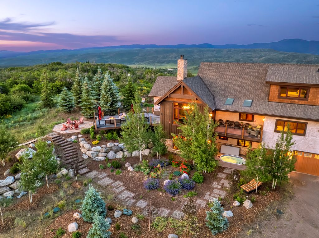 High-angle twilight view of a luxury mountain home at 947 Blue Ridge Rd, Silverthorne, CO, with tiered stone landscaping.
