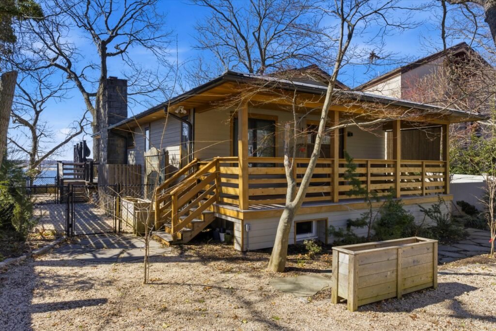 Northport, NY beach house featuring wood-paneled siding, stone chimney, and expansive outdoor living space.