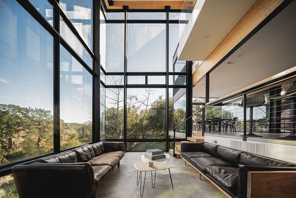 Double-height living room by Finn Kappe in Malibu, featuring floor-to-ceiling glass walls, leather sofas, and panoramic canyon views.