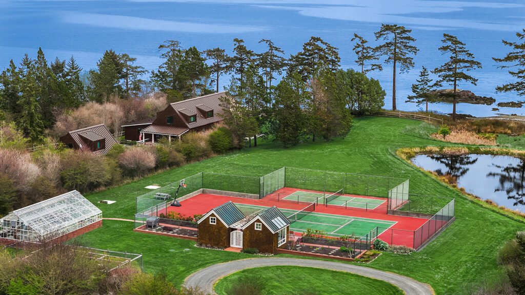 Luxury waterfront estate showcasing a private tennis court, detached guest house, and ocean views.