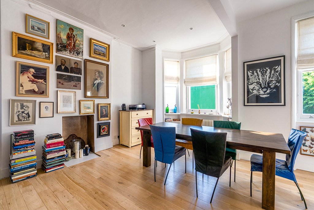 Bright dining room featuring light oak hardwood floors, a large bay window, and character features.
