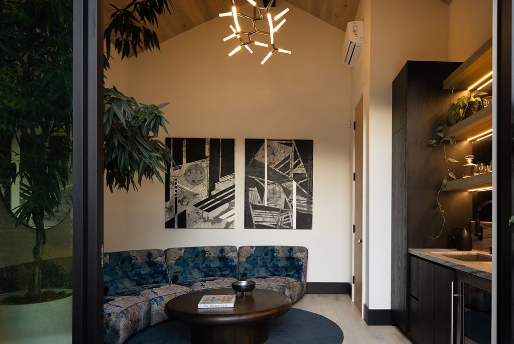 Modern sitting room featuring a vaulted wood ceiling, custom dark cabinetry with integrated lighting, and a curved sectional sofa.
