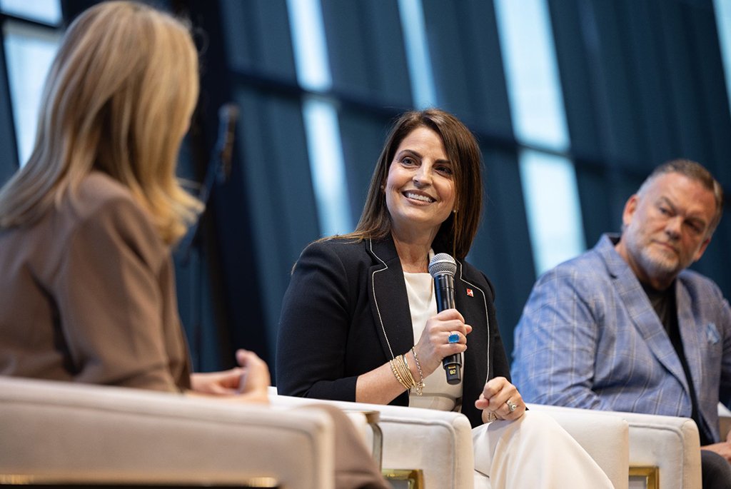 Smiling female professional holding a microphone and speaking during a panel discussion at a business conference