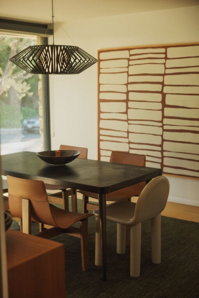 Mid-century modern dining room furniture with large abstract artwork.