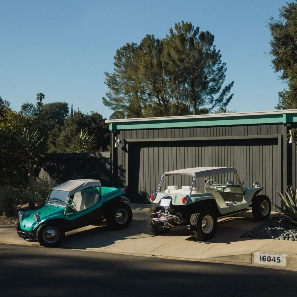 Vintage Meyers Manx dune buggies in a mid-century modern home driveway.