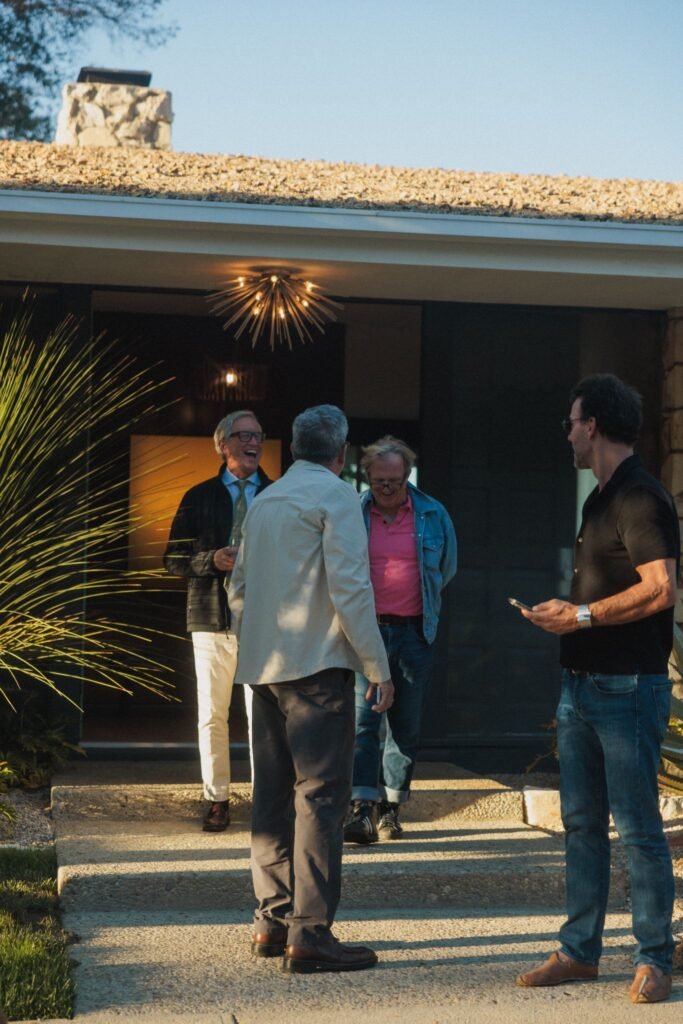 Luxury mid-century modern home entrance with people socializing on the walkway.