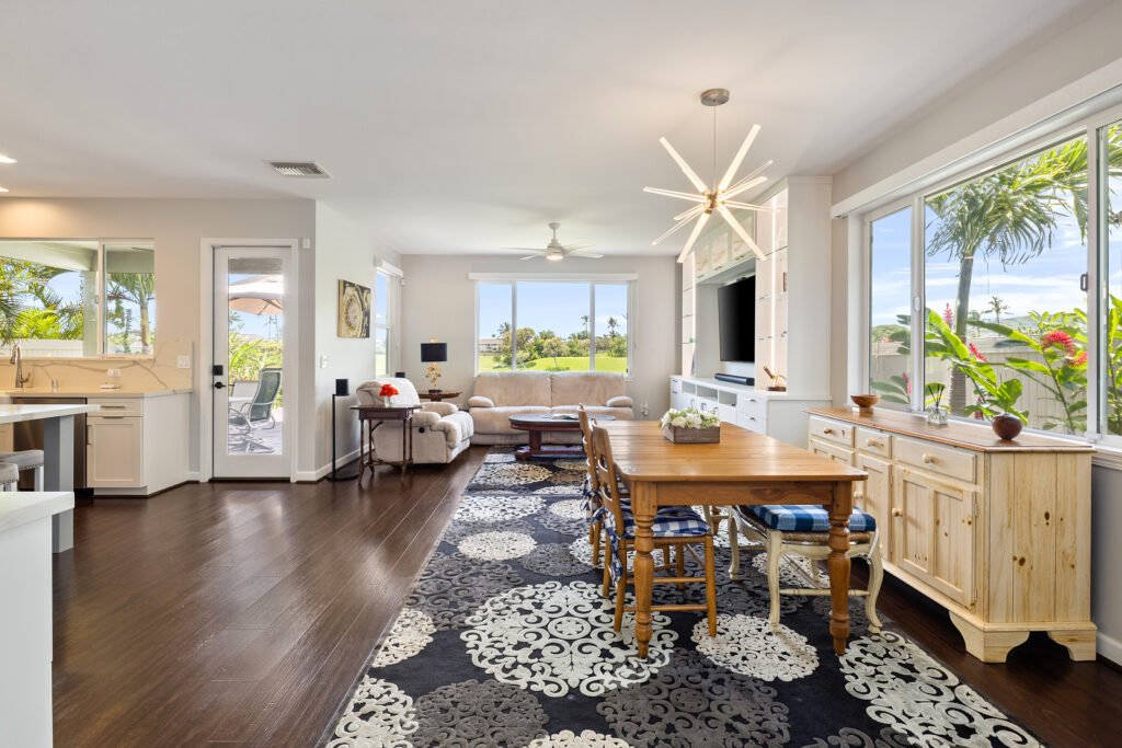 Open-concept floor plan featuring a spacious dining area with a modern starburst light fixture, dark hardwood floors, and a view into the living room.