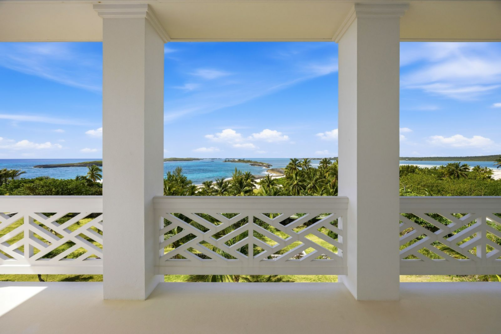Tropical ocean view framed by a white concrete balcony with geometric patterned railings.