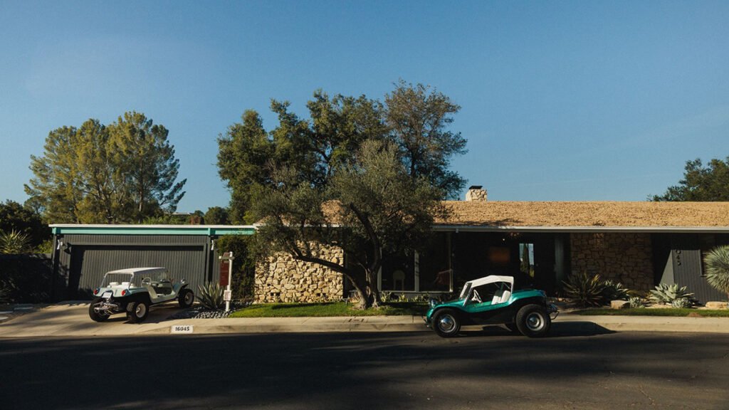 Mid-century modern real estate property with stone exterior and vintage Meyers Manx dune buggie