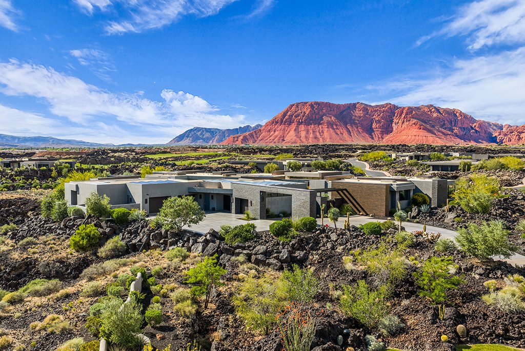 Aerial view of a luxury modern desert estate surrounded by volcanic rock and red rock mountains.