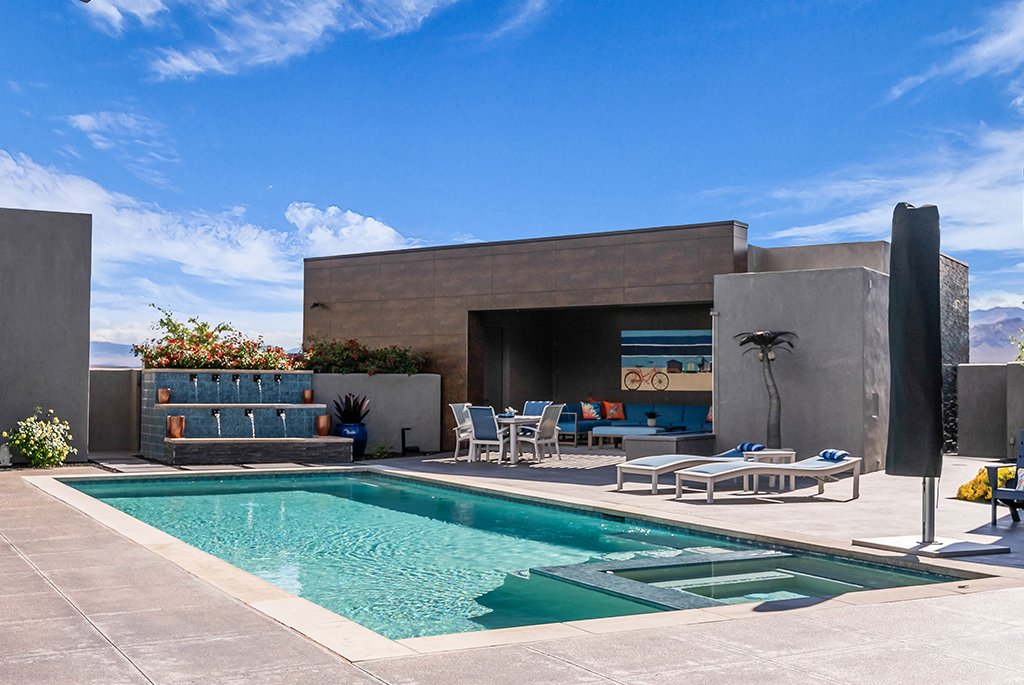 Modern luxury backyard pool area featuring an integrated hot tub and mosaic tile water feature.