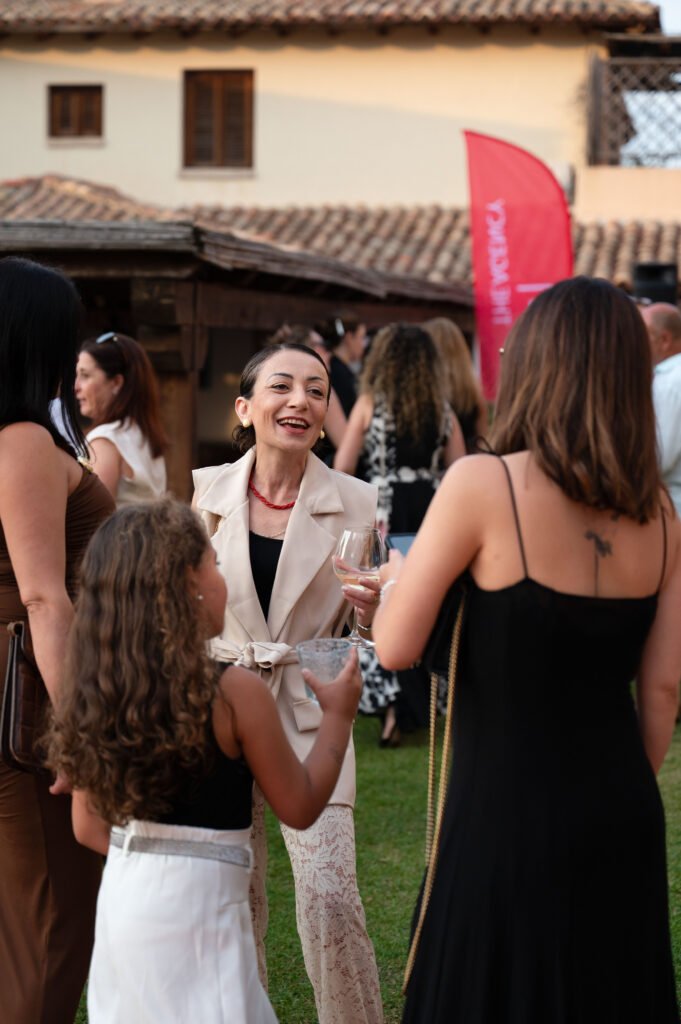 Real estate clients and industry professionals networking at the outdoor launch event for The Agency Sardinia in Puntaldia, Italy.