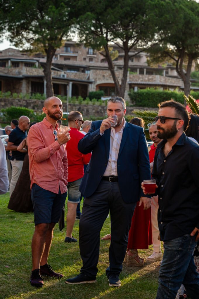 Guests enjoying cocktails and networking at the outdoor opening celebration for luxury property brokerage The Agency Sardinia in Puntaldia, Italy.