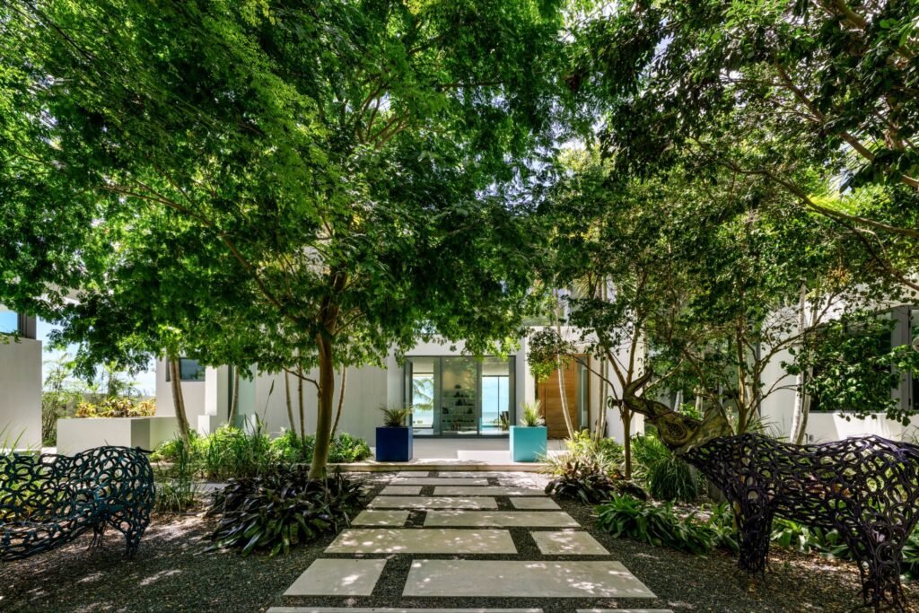 Lush tropical walkway and stone pavers leading to the contemporary entrance of the coastal modernism estate at 19 Avacado Street in Islamorada, Florida.