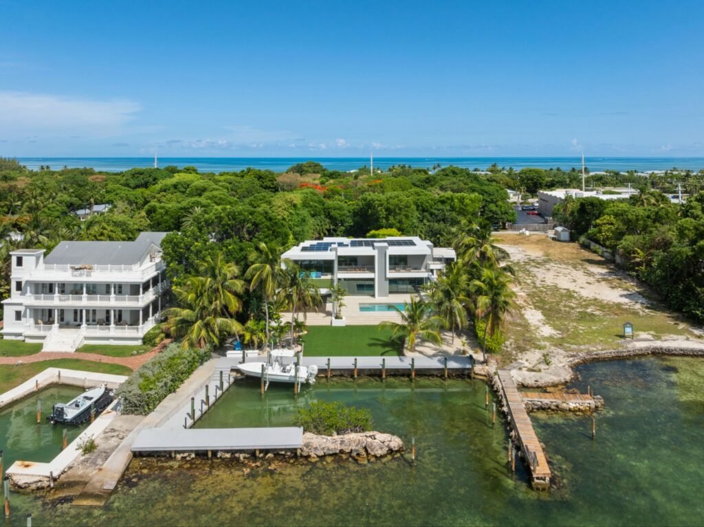Wide aerial drone shot of the coastal modernism waterfront estate at 19 Avacado Street in Islamorada, showing the two-parcel lot, private boat dock, and expansive bayfront.