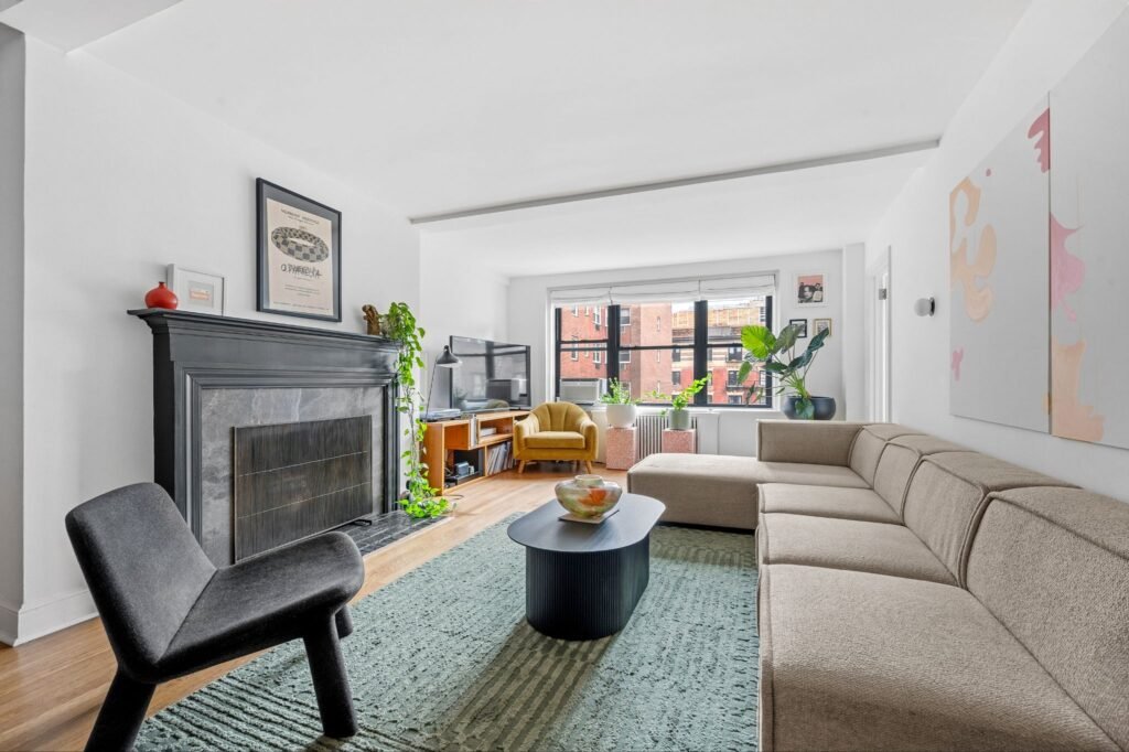 Sun-filled pre-war 1-bedroom apartment living room with a decorative fireplace and open city views at 140 East 28th Street in Kips Bay, Manhattan.