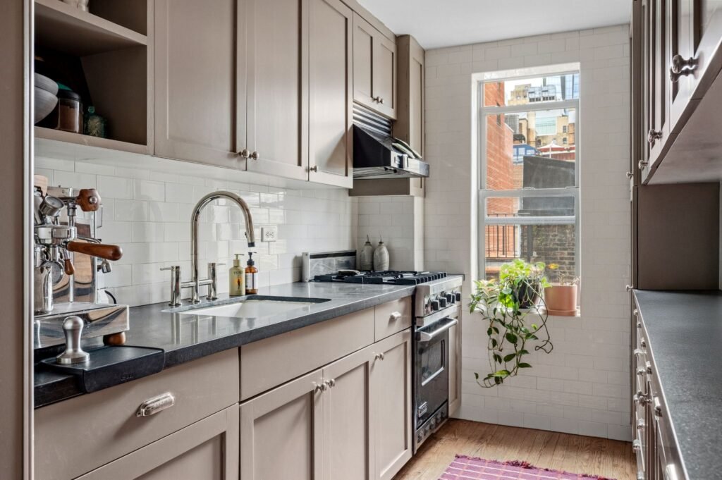 Updated pre-war apartment kitchen at 140 East 28th Street in Manhattan, featuring top-notch appliances, a gas range, and a window with city views.