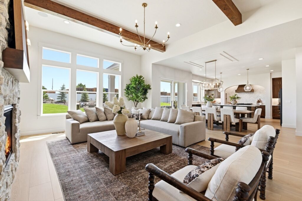 Open-concept living and dining area with wide-plank oak floors, exposed wood beams, and a large chandelier at 7042 E Chicken Hawk Loop in Nampa, Idaho.