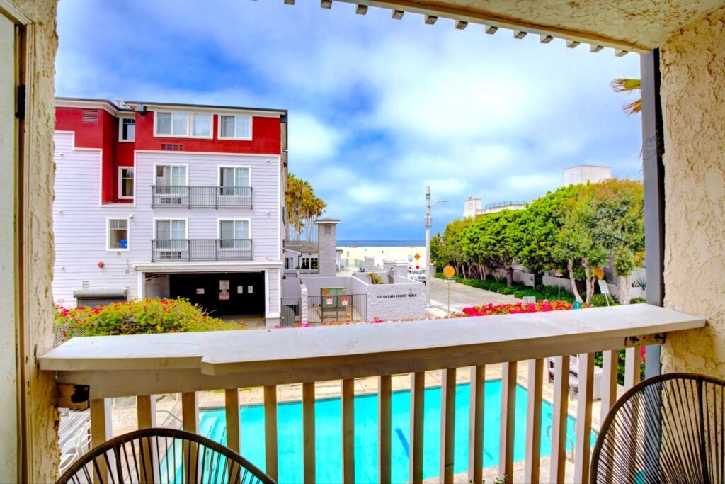 Breezy apartment patio balcony view overlooking a heated community pool and a glimpse of Venice Beach at 22 Navy Street in Venice, California.