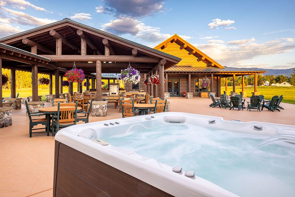 A large outdoor hot tub overlooking the covered patio dining area and al fresco entertainment space at A River's Ranch.