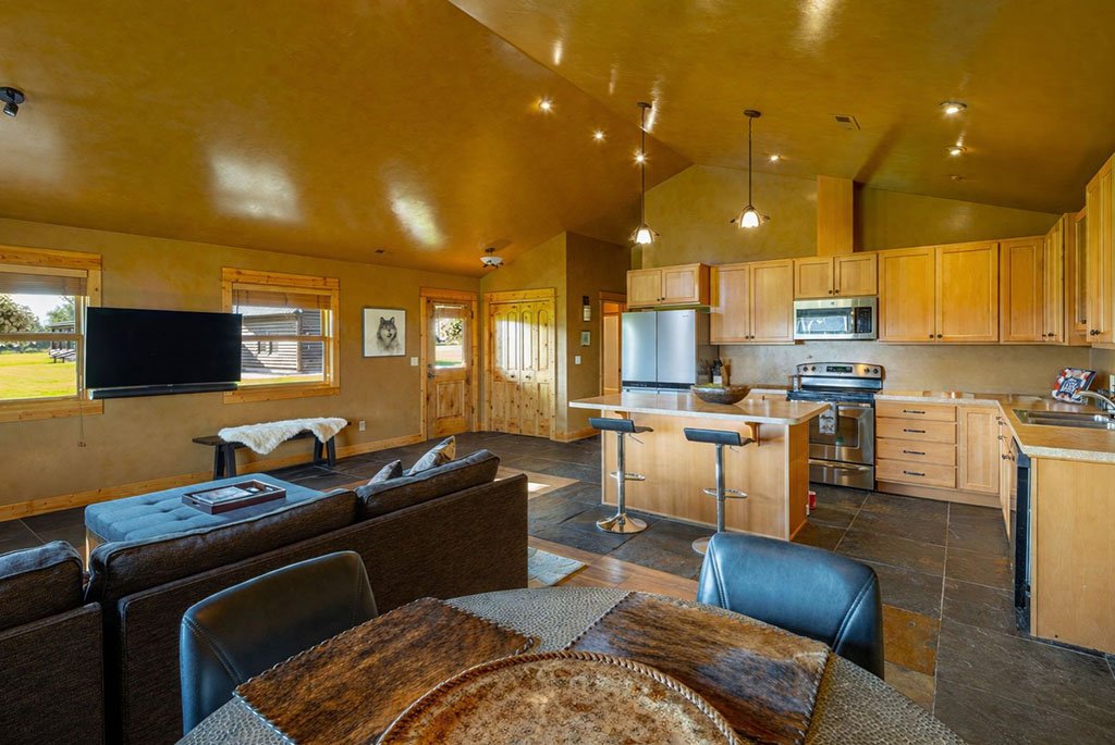 The open kitchen, dining, and living area inside the private guest house at A River's Ranch featuring modern appliances and a central breakfast bar island.