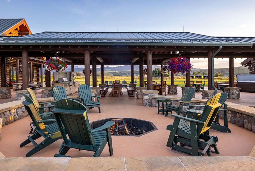The outdoor kitchen and fire pit patio at A River's Ranch, designed for large gatherings with multiple dining tables and scenic mountain views.
