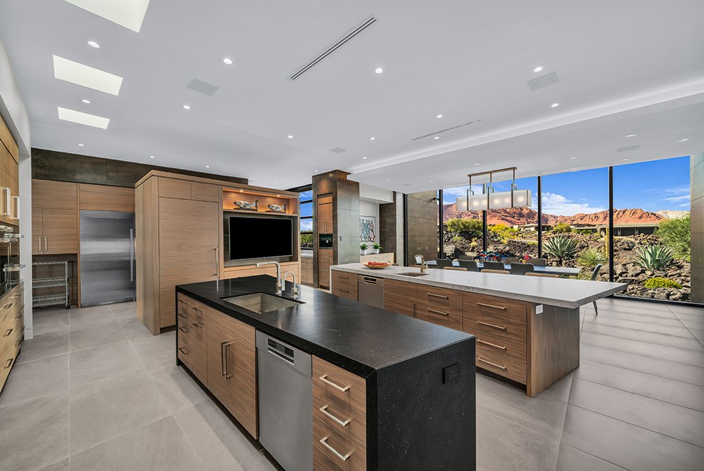 Modern luxury kitchen featuring double islands, custom wood cabinetry, and scenic desert views.