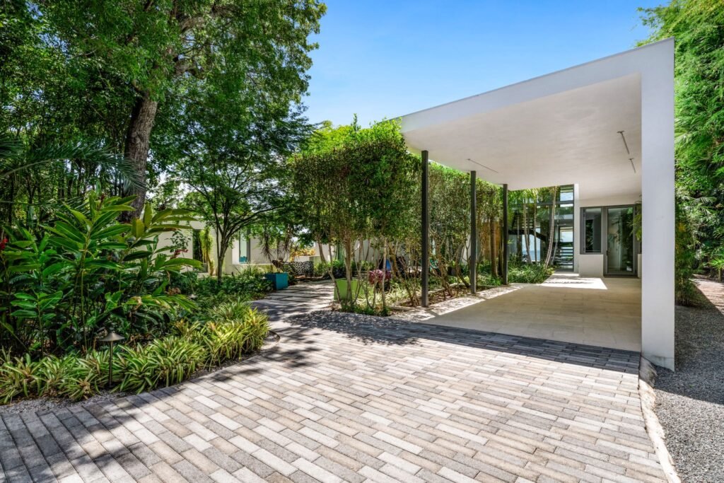 Modern covered carport and paved driveway at the 19 Avacado Street estate in Islamorada, showing the coastal modernism architecture by Charles Vincent George Architects amidst lush native landscaping.