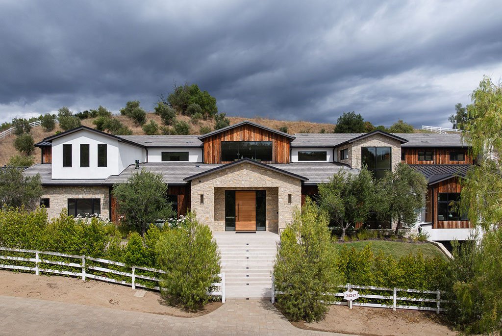 Modern luxury estate in Hidden Hills, California featuring a striking stone entryway, natural wood siding, and clean white stucco architecture