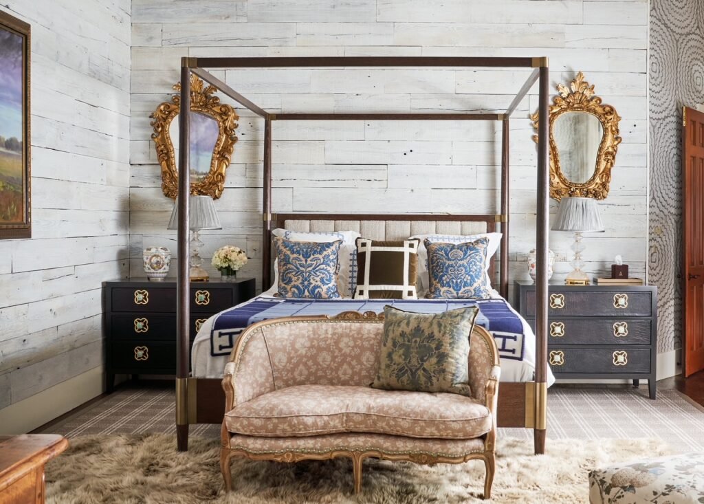 A luxury bedroom interior at the 50-acre legacy estate outside Dallas, Texas, custom designed by Kirsten Kelli Interior Design, featuring a dark wood canopy bed, ornate gold-framed mirrors, white shiplap walls, and a vintage-style settee.