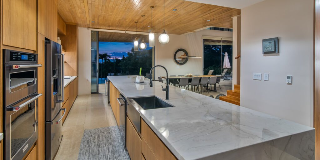 Modern luxury kitchen with marble island and wood ceilings at Dos Monitos Luxury Compound in Costa Rica.