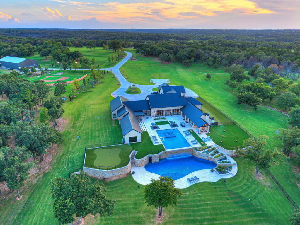 Aerial view of the multi-level pool, putting green, and estate grounds at 3003 Country Club Drive in Stillwater Oklahoma.