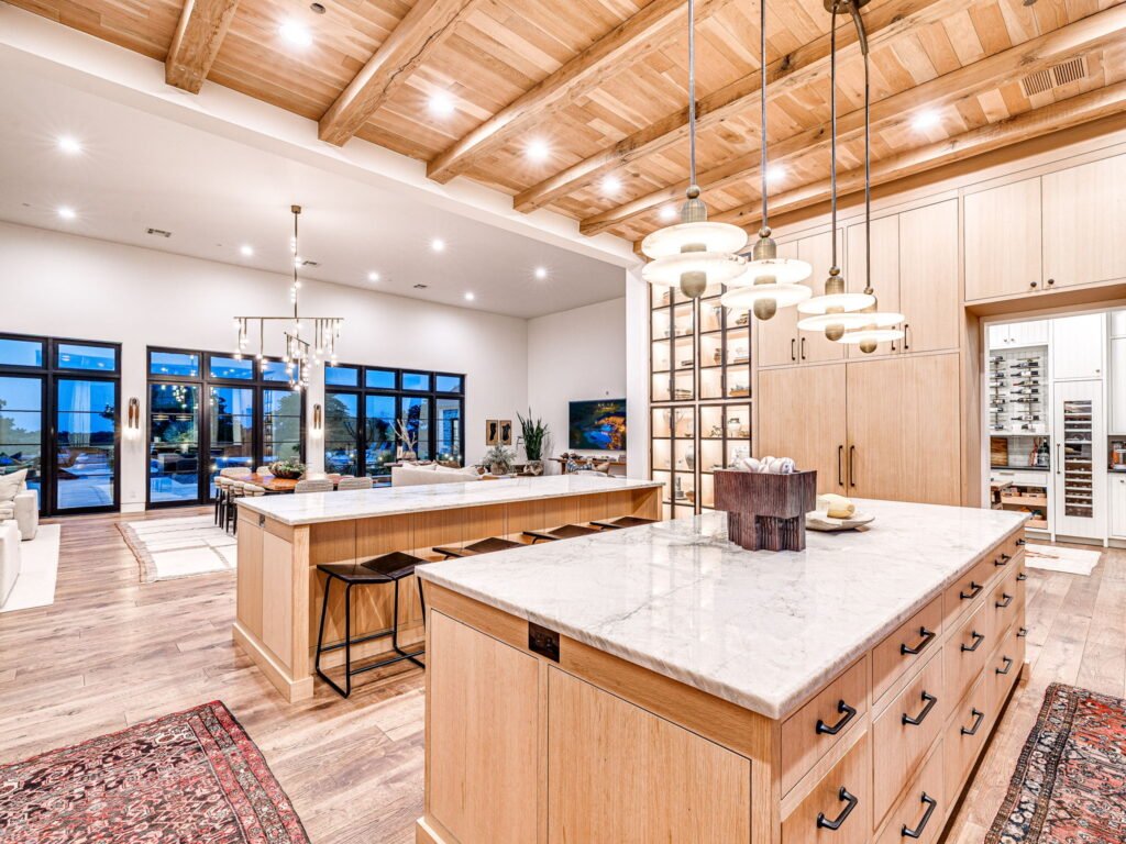 Modern open kitchen with dual marble islands and wood ceilings at 3003 Country Club Drive in Stillwater Oklahoma.