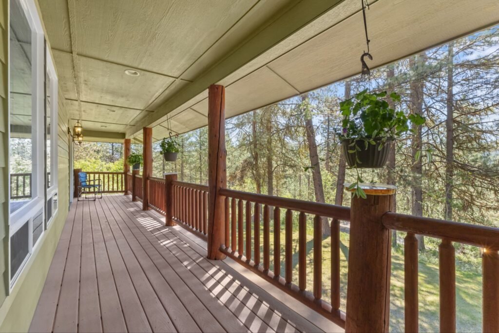 Covered wooden deck with log railings overlooking a pine forest at 14 White Mesa in Banks Idaho.