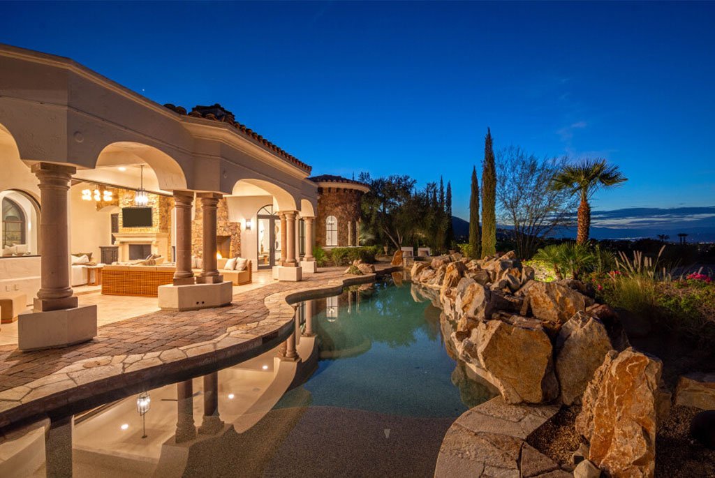Illuminated luxury villa pool and outdoor stone loggia at night at 49769 Desert Vista Drive in Palm Desert California.