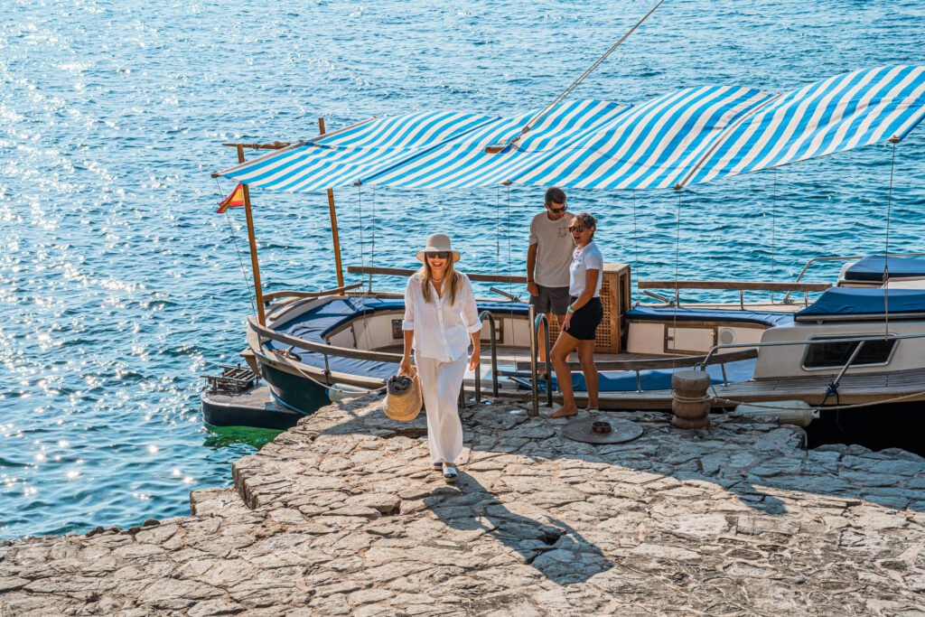 A boat docked at the private stone jetty of a frontline Mallorca villa, showcasing direct sea access and coastal lifestyle.