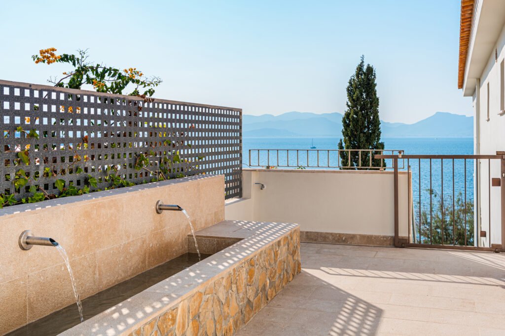 Outdoor stone terrace with a modern water feature overlooking the Mediterranean Sea at a luxury Mallorca estate.