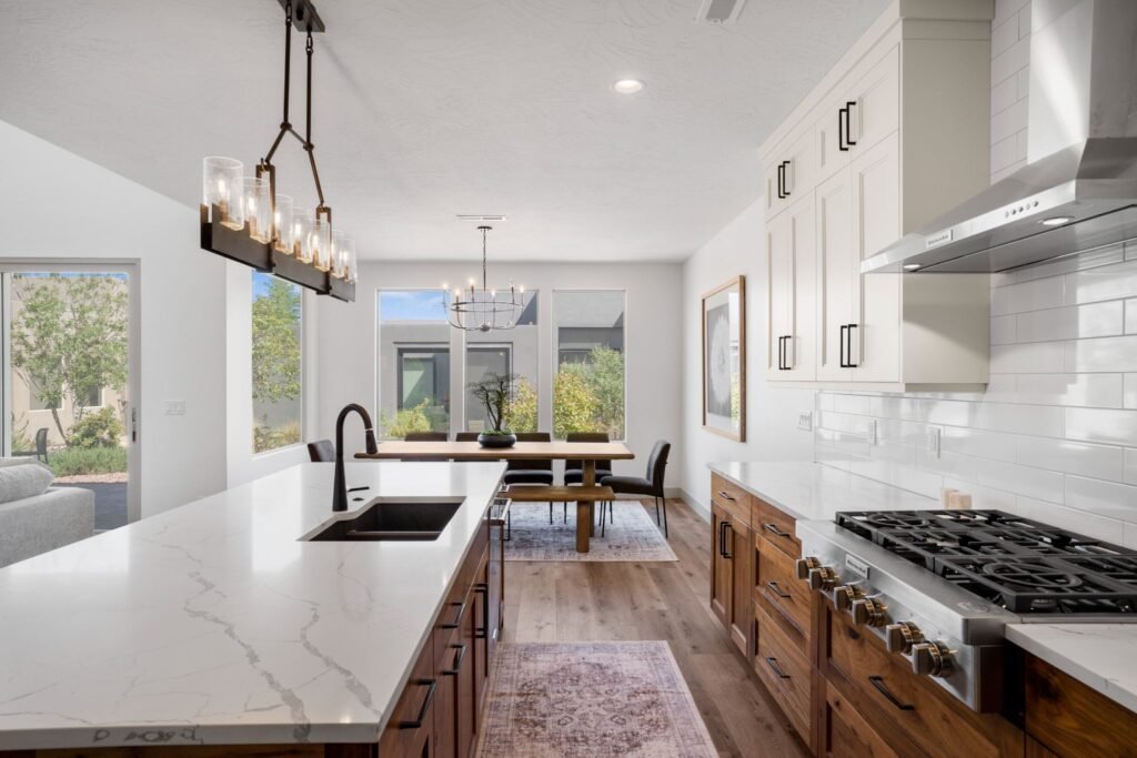 Open-concept gourmet kitchen and dining area at Tava Resort, Utah, featuring custom wood cabinets, modern light fixtures, and bright windows.